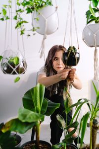 Portrait of beautiful young woman holding potted plant