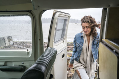 Teenage girl getting into vintage van on rainy day