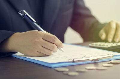 Midsection of businessman writing in paper at office