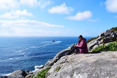 Woman sitting on rock formation against sea at beach