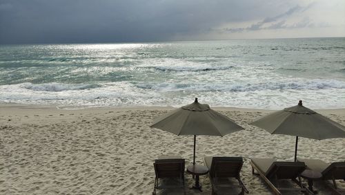 Chairs on beach by sea against sky