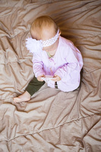 High angle view of cute girl sitting on bed at home