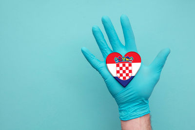 Close-up of hand holding red over blue background