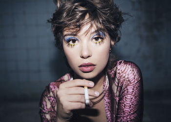 Portrait of young woman smoking cigarette in room