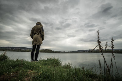 Rear view of woman standing by sea against sky