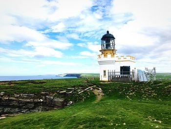 Lighthouse by building against sky