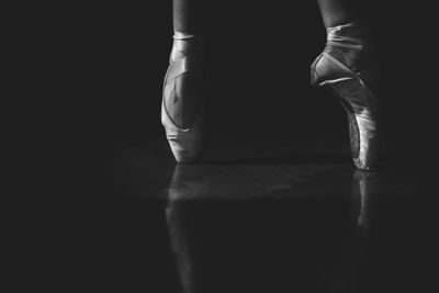 Low section of ballerina balancing on toe against black background