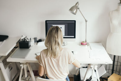 Rear view of woman sitting on table