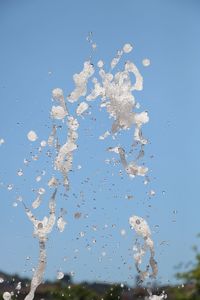 Low angle view of water splashing against clear blue sky