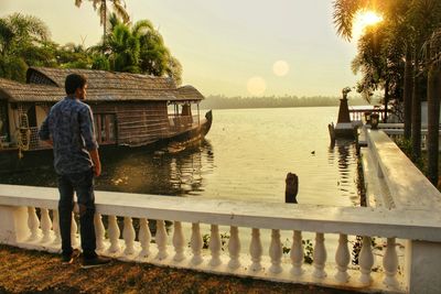 Rear view of men standing on lake against sky