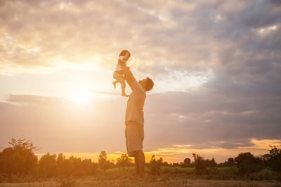 People standing on field against sky during sunset