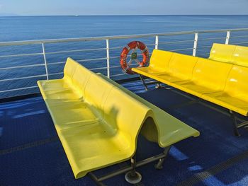 High angle view of yellow chair by sea against sky