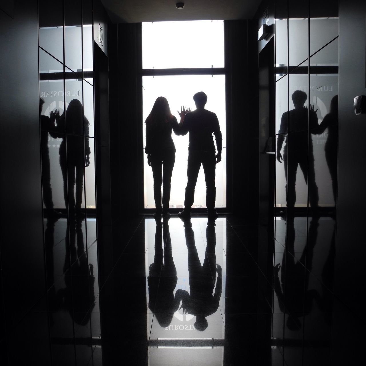 indoors, men, silhouette, lifestyles, person, window, standing, glass - material, full length, flooring, rear view, reflection, transparent, architecture, medium group of people, leisure activity, waiting, built structure