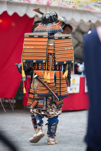 Rear view of man in costume walking on road during event