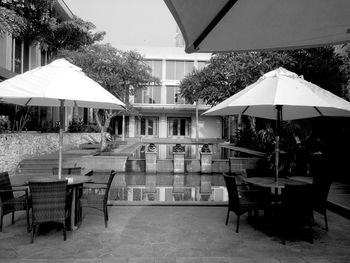 Chairs and tables at sidewalk cafe against sky