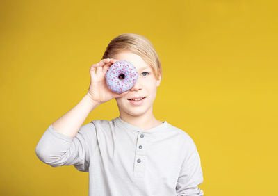 Portrait of young woman wearing mask against yellow background