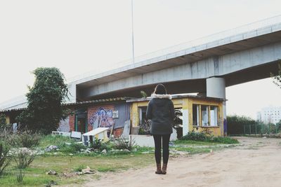 Rear view of man walking against built structure