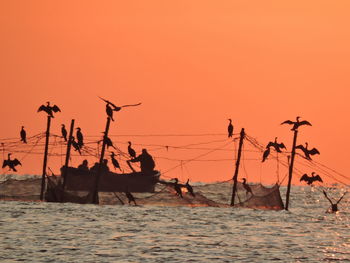 Silhouette people by sea against clear sky during sunset