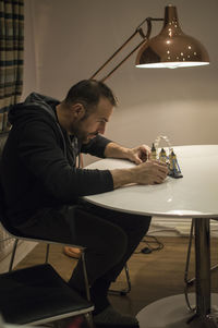 Side view of young man sitting on table