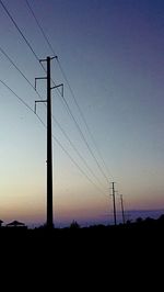 Low angle view of silhouette electricity pylon on field against sky