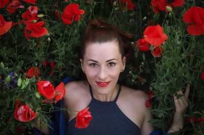 Directly above shot of woman lying amidst poppy on field