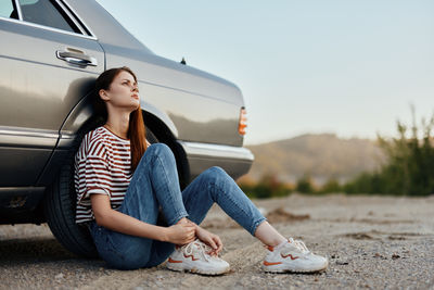 Low section of woman sitting on car