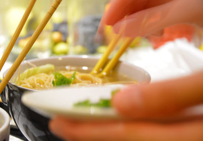 Close-up of hand holding bowl of soup