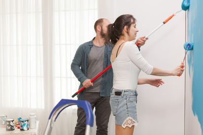 Young couple holding hands standing against wall