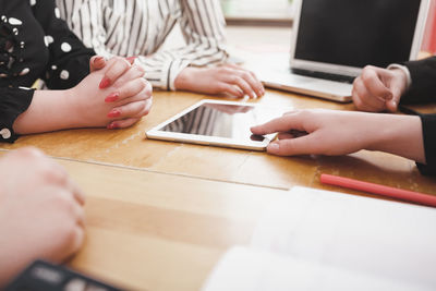 Midsection of woman using smart phone on table