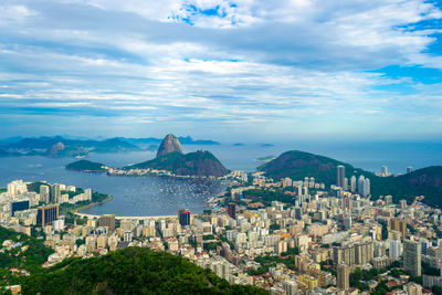 Aerial view of city by sea against sky