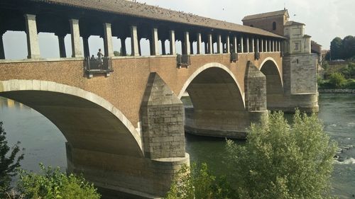 Arch bridge over river against sky