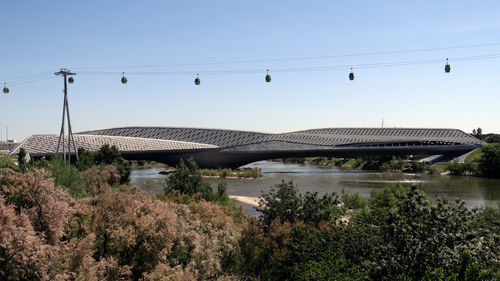 Overhead cable car over bridge pavilion against sky