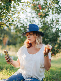 Full length of woman using mobile phone on field