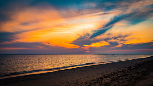 Scenic view of sea against dramatic sky during sunset