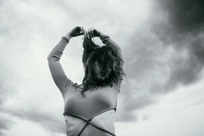 Rear view of woman with arms raised against sky