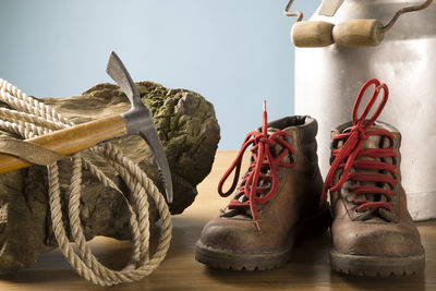 Close-up of piolet and rope on wood by boot on table