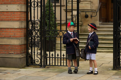 Boy and girl talking while standing by school gate