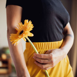 Midsection of woman holding yellow flower