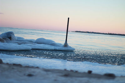 Surface level of frozen sea against sky during sunset