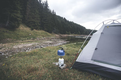 Camping stove and tent on field against sky