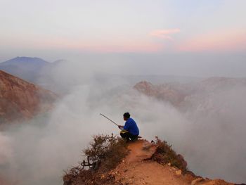 Rear view of man on mountain against sky