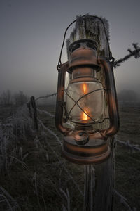 Close-up of illuminated lantern on field against sky at dusk
