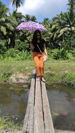 Young woman standing by tree in park