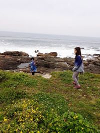 Rear view of friends on beach against sky