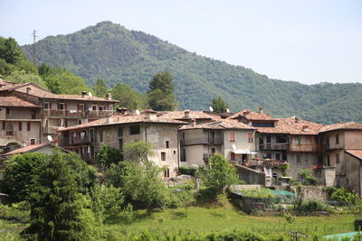 Houses by trees and mountains against sky