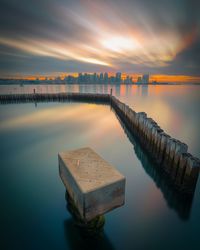 Pier over lake against sky during sunset