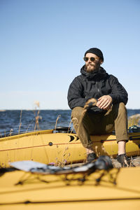 Man sitting on kayak on coast and looking away