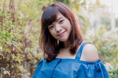 Portrait of young woman standing against plants