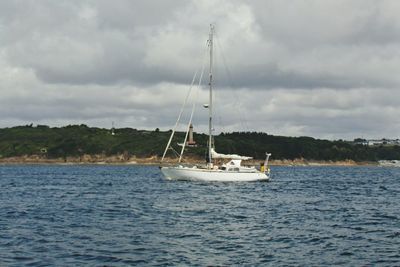 Boats sailing in sea against cloudy sky