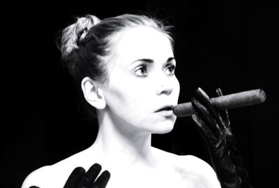 Portrait of woman smoking cigarette against black background